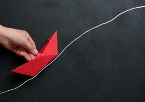 vrouw hand- Holding een rood papier boot, concept van begeleiding en ondersteuning foto