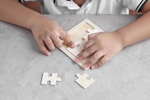Aziatische kleine jongen die houten puzzel speelt foto