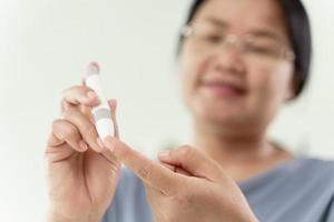 vrouw gebruikt lancet op vinger die bloedsuikerspiegel controleert met glucosemeter foto