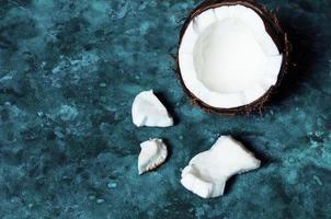 open kokosnoot ligt op een donkerblauwe achtergrond naast gebroken stukken foto