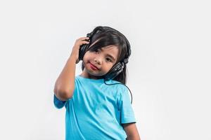 klein meisje luisteren naar muziek op draadloze koptelefoon. foto