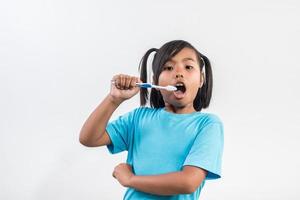 klein meisje haar tanden poetsen in studio opname. foto
