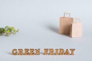 groen vrijdag concept belettering, papier Tassen en bladeren Aan groen achtergrond foto