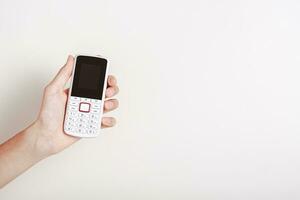 hand- Holding een oubollig wit druk op de knop telefoon foto