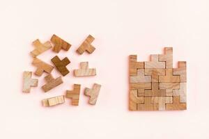 organisatie en bestellen. houten puzzel stukken zijn gestapeld correct en chaotisch verspreide in wanorde Aan een roze achtergrond foto