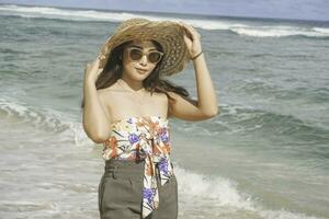 een gelukkig jong Aziatisch vrouw vervelend strand hoed is poseren naar de camera Bij de strand in gunungkidul, Indonesië foto