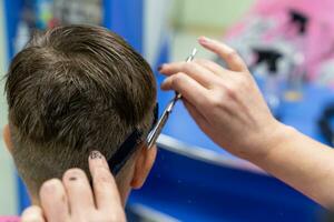 jongen in een schoonheid salon maakt een elegant kapsel foto