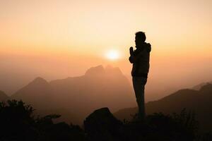 silhouet van een mannen is bidden naar god Aan de berg. bidden handen met geloof in religie en geloof in god Aan zegen achtergrond. macht van hoop of liefde en toewijding. foto