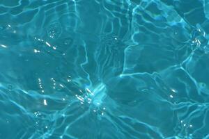 onscherp wazig transparant blauw gekleurde Doorzichtig kalmte water oppervlakte structuur met spatten reflectie. modieus abstract natuur achtergrond. water golven in zonlicht met kopiëren ruimte. blauw waterverf schijnen. foto