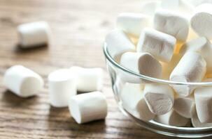 kom van marshmallows Aan de houten achtergrond foto