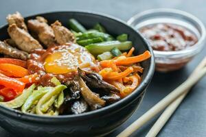 kom van Bibimbap Aan de houten tafel foto