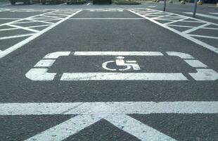 handicap symbool Aan weg, verkeer en voetgangers in achtergrond foto