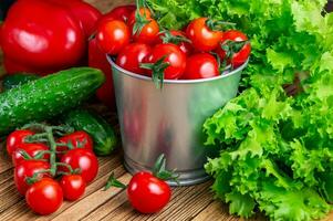 reeks van groenten voor salade, komkommers, klok pepers, vers rood kers tomaten Aan een houten tafel top.top visie. oogst. natuurlijk voedsel. foto