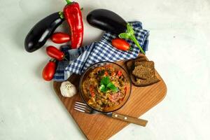 populair groente schotel van wereld keuken in een glas kom top visie, ajapsandali, pinjur, gestoofd groenten, aubergine kaviaar. hoofd ingrediënten aubergines, tomaten, klok pepers, knoflook, specerijen. foto