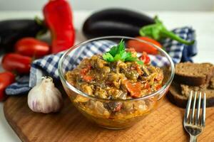 populair groente schotel van wereld keuken in een glas kom detailopname - ajapsandali, pinjur, gestoofd groenten, aubergine kaviaar. hoofd ingrediënten aubergines, tomaten, klok pepers, knoflook, specerijen. foto