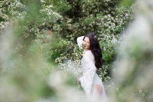 portret van een mooie jonge vrouw in het park in bloeiende takken foto