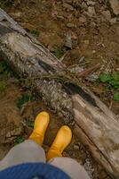 vrouw poten in geel rubber laarzen terwijl wandelen in de bergen. vallen lokaal reis. foto