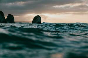 de rots formaties in de oceaan Bij zonsondergang foto