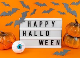 lichtbak met vrolijke halloween-uitdrukking met pompoenen, vleermuizen en oogbol foto