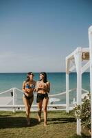 glimlachen jong Dames in bikini genieten van vakantie Aan de strand foto