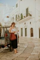 vrouw toerist met papier stad kaart Aan versmallen straten van ostuni, Italië foto