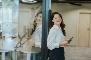 jong vrouw met digitaal tablet staand in de modern kantoor foto