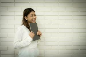 mooi Aziatisch bedrijf vrouw gevoel gelukkig ze omhelsd de tablet met glimlach Aan haar gezicht. foto