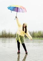 mooie donkerbruine vrouw die kleurrijke paraplu in de regen houdt foto