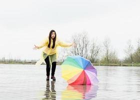 grappige vrouw die kleurrijke paraplu buiten in de regen vangt foto