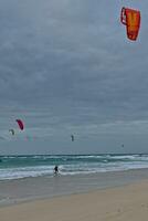 zomer landschap met de oceaan met donker bewolkt golven en surfermi uitrusting met parachutes drijvend Aan de kust foto