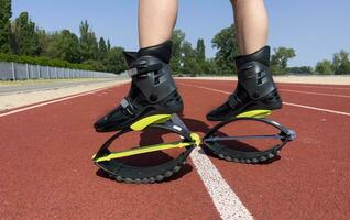 kangoo springen schoenen. een meisje Toneelstukken sport- in een stadion vervelend kangoo jumping schoenen. foto