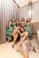 een groep van Aziatisch Dames in glamoureus en luxueus kleren zijn zittend Aan de sofa met hun vrienden na feesten foto