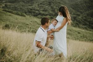 jong gezin met schattige kleine jongen die plezier heeft buiten in het veld foto