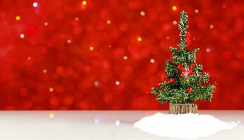 speelgoed- Kerstmis boom met rood decor Aan een wit tafel tegen een achtergrond van rood en veelkleurig onscherp lichten foto