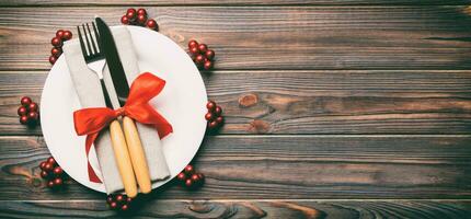 top visie banier van bord, vork en mes geserveerd Aan Kerstmis versierd houten achtergrond. nieuw jaar vooravond concept met kopiëren ruimte foto
