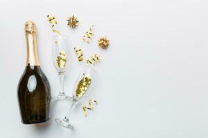 fles van Champagne met bril en kleurrijk confetti Aan gekleurde achtergrond. top visie villen leggen foto
