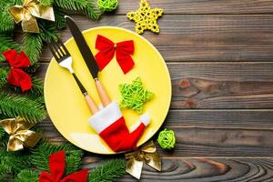 top visie van vork, mes en bord omringd met Spar boom en Kerstmis decoraties Aan houten achtergrond. nieuw jaar vooravond en vakantie avondeten concept foto