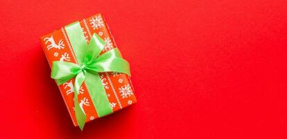 geschenk doos met groen boog voor Kerstmis of nieuw jaar dag Aan rood achtergrond, top visie met kopiëren ruimte foto