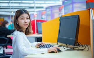 mooi Aziatisch bedrijf vrouw is zittend en gebruik makend van een computer terwijl geconfronteerd de camera, digitaal marketing. foto