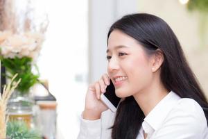 jonge Aziatische vrouw praten telefoon en glimlach in de coffeeshop. foto