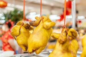 gekookt kip en hing met touwen voor uitverkoop naar Chinese naar betalen hulde naar hun voorouders. gedurende Chinese nieuw jaar festival. verkocht Bij voedsel afdeling van een supermarkt. selectief focus, wazig achtergrond foto