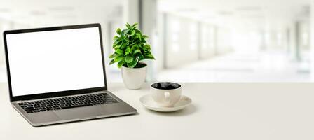 de concept voor bedrijf, technologie, internetten, ontwerp, programmeur. blanco wit scherm laptop, koffie beker, en vaas zijn geplaatst Aan een wit bureau in kantoor. dichtbij omhoog, selectief focus foto