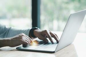 Mens toepassingen zijn vinger naar druk op knop naar beurt uit, gesloten, shut naar beneden laptop computer geplaatst Aan bureau, is tijd naar af hebben elk dag voordat gaan huis voor besparing energie. na besparing allemaal gegevens bedrijf werk. foto