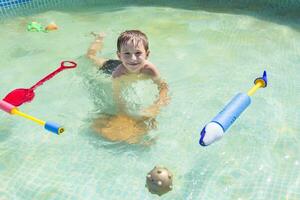een kind zwemt in de zwembad met speelgoed. jongen baadt in water foto