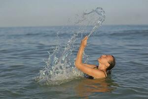 midden- leeftijd vrouw in de zee met verstuiven van water. foto
