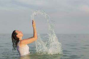 midden- leeftijd vrouw in de zee met verstuiven van water. foto