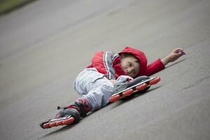 de jongen in rol skates aan het liegen Aan de bestrating.de kind in rol skates viel foto