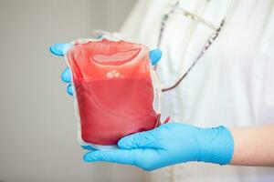 bloed plasma in de centrum van transfusiologie en bijdrage. dichtbij omhoog de bloed zak in de laboratorium in de handen. foto