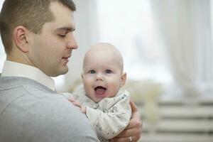 vader houdt baby.vrolijk baby in de armen van de ouder foto