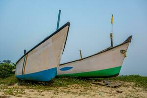 oud visvangst boten in de zand Aan de oceaan in Indië Aan blauw lucht achtergrond foto